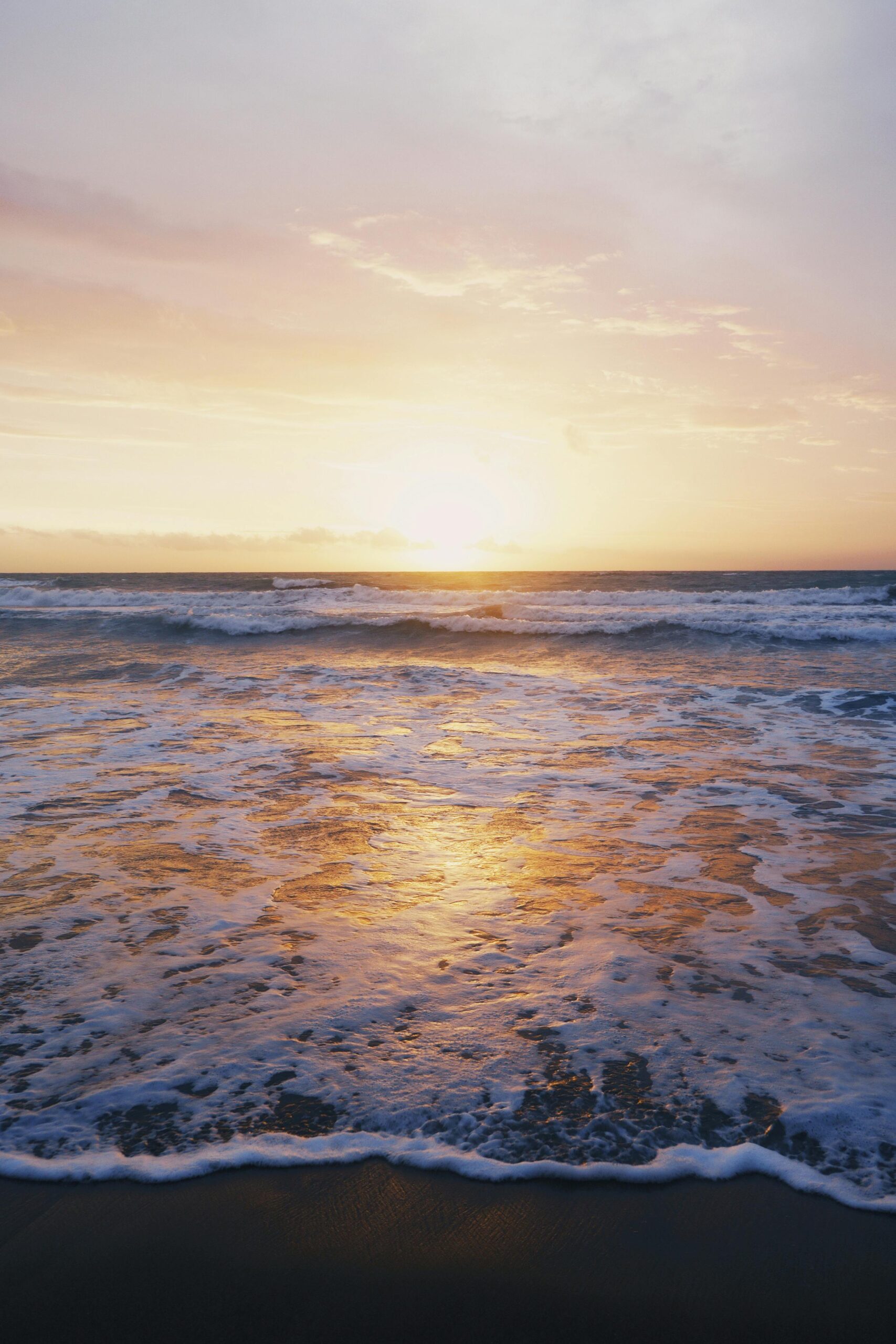 A serene ocean sunset with golden light reflecting off the waves.